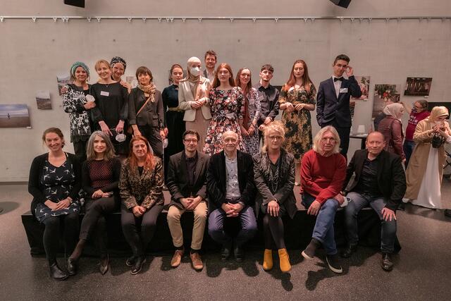 Die jungen Autoren und Autorinnen mit den Projektverantwortlichen Sabine Kerschbaum und Maynat Kurbanova sowie Fotografin Zoe Goldstein (stehend v.l.n.r.) und den prominenten Lesern und Leserinnen bei der Vernissage in Linz. | Foto: ml-media