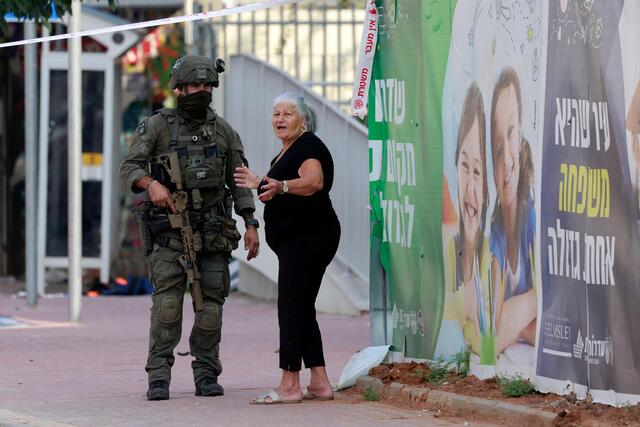 Eine Anwohnerin steht mit einem israelischen Soldaten in der Nähe einer abgesperrten israelischen Polizeistation, die bei den Kämpfen beschädigt wurde. | Foto: MENAHEM KAHANA / AFP / picturedesk.com