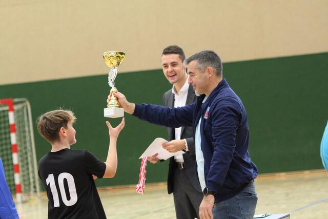Turnier-Organisator Matthias Froschauer übergibt den Siegerpokal.
