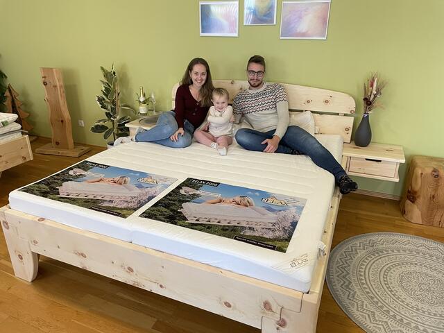 Samantha und David posieren mit Tochter Eleanora (3) auf einem der Zirbenbett-Ausstellungstücke im Schauraum des "Schlafstudio Bieber". | Foto: Gernot Heigl