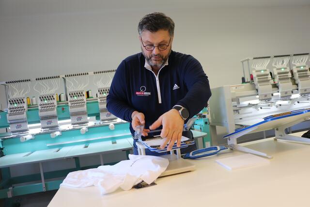 Harald Kolar zeigt das Einspannen in den Stickrahmen, alles andere macht die Maschine | Foto: Edith Ertl