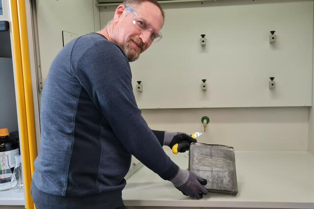 Zum Schutz vor dem Blei hat Thomas Hofer (Mitarbeiter Landeslabor) Handschuhe und Schutzbrille auf. Zudem wird die Zeitkapsel unter einem Luftabzug im Labor geöffnet. | Foto: Land Salzburg/Bernhard Kern