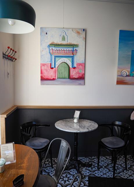 Geschmackvolle Bistrotische verteilen sich im Raum und werden umgeben von kunstvollen Bildern. | Foto: Anna Rauchecker