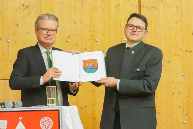 Landeshauptmann Christopher Drexler überreicht symbolisch das Gemeindewappen an Bürgermeister Franz Nöhrer