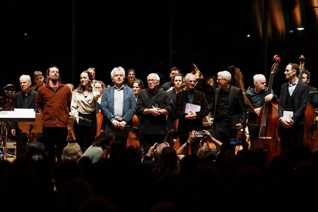 Die Komponist:innen des 23. InnStrumenti-Uraufführungskonzerts Philipp Ossanna, Ivana Radovanovic, Martin Lichtfuss, Gunter Schneider und Hubert Stuppner gemeinsam mit Dirigent Gerhard Sammer und Moderator Benedikt Grawe sowie dem Tiroler Kammerorchester InnStrumenti. | Foto: Amir Kaufmann