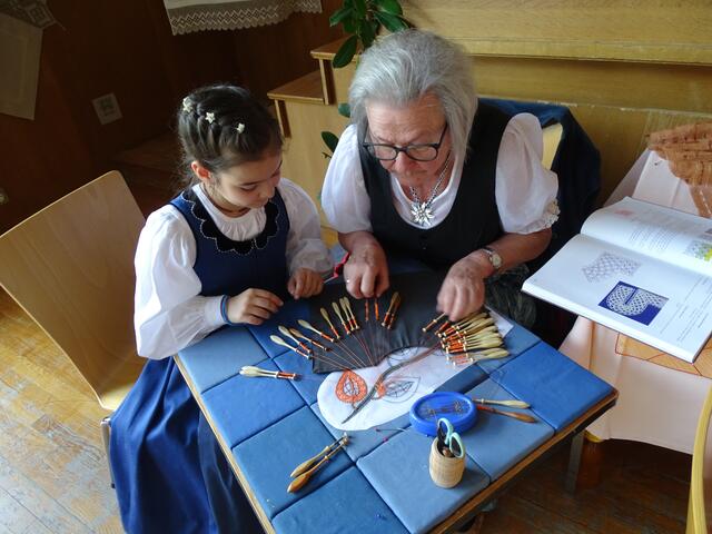 Junge Augen beobachten erfahrene Hände beim Klöppeln - Handarbeitsausstellung der Radentheiner Trachtengruppe