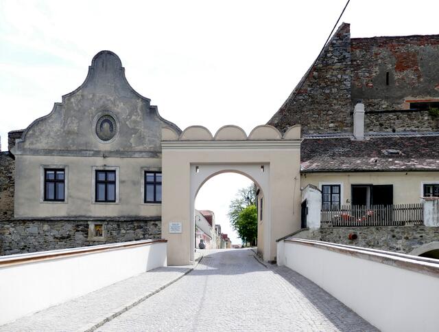 
Raabser Tor oder Unteres Tor ist das zweite der beiden stadttore. Es war durch einen hohen Wehrturm geschützt, der 1863 vollständig abgetragen wurde. Über dem Torbogen, Rollschlitze für die Zugbrücke. Das Haus an der Stadtmauer rechts vom Raabser Tor war das Torwärterhaus. Im Haus links vor dem Raabser Tor war einige Zeit die Schule untergebracht. Vor dem Tor finden Sie Reste des Stadtgrabens. Die Häuser jenseits des Grabens sind direkt in den Mauern der Vorwerke hineingebaut. Das kleine Haus ganz rechts am Weg zur Promenade (Raabser Tor 7) war das Mauthaus.