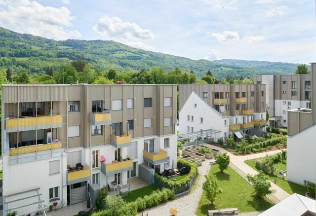 Salzburg: Die Fenster waren undicht, die Balkone baufällig, die Heizkosten exorbitant hoch. Statt einer klassischen Sanierung wurde der Weg ressourcenschonenden Weiterbauens eingeschlagen: Den Anfang machte ein Forschungsprojekt des Salzburger Instituts für Raumordnung und Wohnen (SIR). Im Zuge der darauffolgenden Revitalisierung wurde der Wohnungsbestand umgebaut und von 75 auf 99 Wohnungen erweitert. Hinter der Aufstockung verbirgt sich eine Holzhybrid-Konstruktion mit tragenden KLH-Wänden, Holzlattenfassade und Holzwolle-Zellulose-Dämmung. Beheizt wird die Anlage mittels Pellets, Wärmepumpe und Wärmerückgewinnung aus den Abwässern der hier wohnenden Menschen. Die alte Silhouette blieb als symbolisches Zitat für Weiterbauen bewusst erhalten. | Foto: Lukas Schaller
