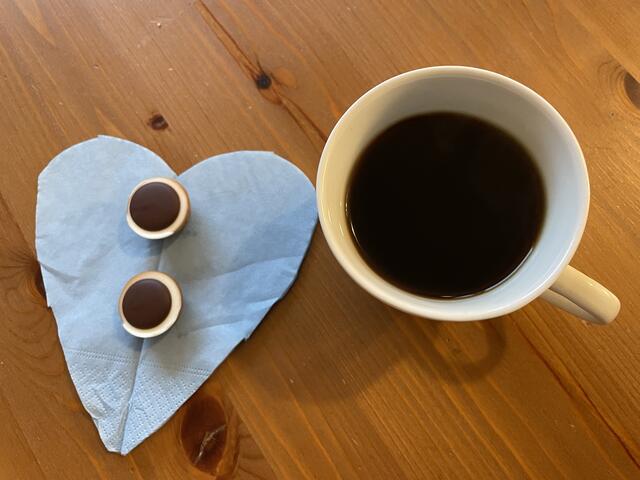 Minimal-Frühstück: Pralinen auf einem Herz mit Kaffee.