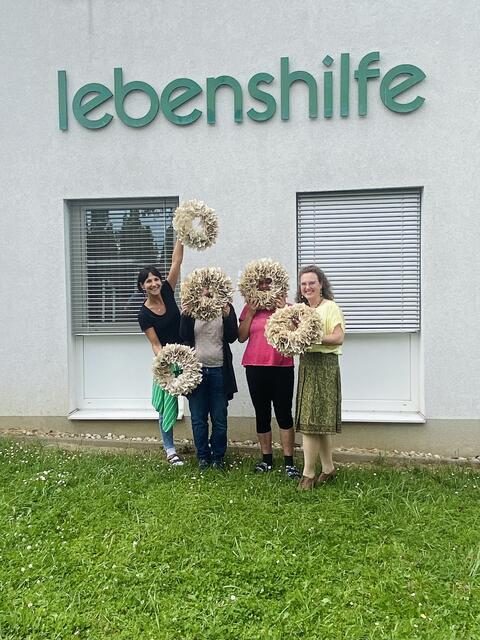 Irene Marinelli und Bernadette Hartl (re.) mit zwei Beschäftigten und deren fertige Buchseitenkränze | Foto: Lebenshilfe Steyr
