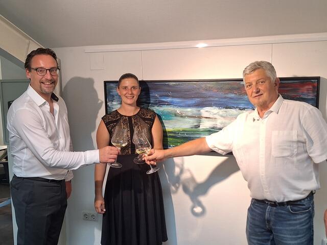 Christian Pfurtscheller und Denise Flohrer stoßen mit dem Erpfendorfer Künstler Manfred Folie auf die erfolgreiche Ausstellung an         