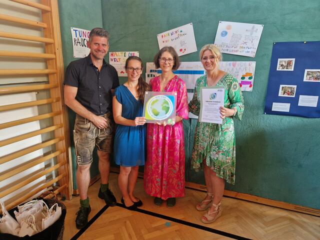 Von links: Bgm. Herbert Schober, Eva Glück (Klimabündnis), Iris Gruber-Auerbach (Lehrerin der dritten Klasse) und Direktorin Michaela Geier bei der Übergabe der Beitrittsurkunde vor der 50/50 Plakatausstellung. | Foto: Gemeinde Grödig