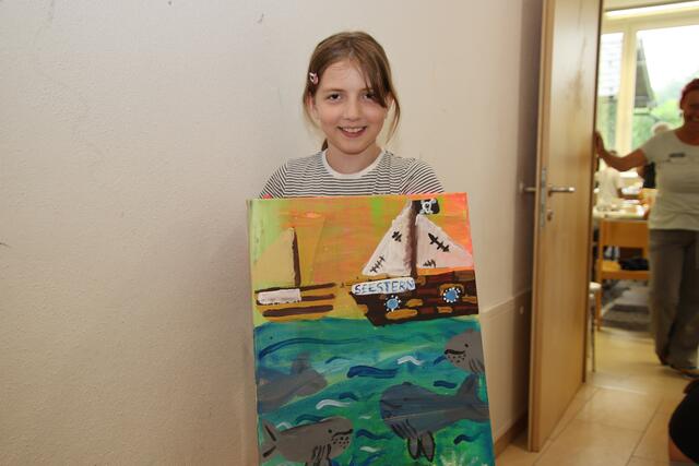 Sarah präsentiert stolz ihr fertiges Kunstwerk.