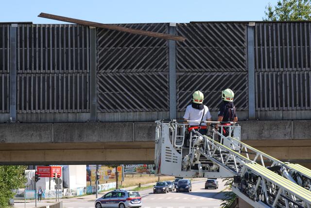 Starke Verwitterung an Lärmschutzwand einer Eisenbahnbrücke in Wels-Vogelweide: Die Feuerwehr konnte die lose gewordene Latte sicher entfernen.