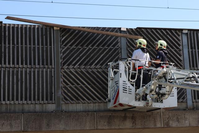 Starke Verwitterung an Lärmschutzwand einer Eisenbahnbrücke in Wels-Vogelweide: Die Feuerwehr konnte die lose gewordene Latte sicher entfernen.