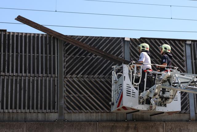 Starke Verwitterung an Lärmschutzwand einer Eisenbahnbrücke in Wels-Vogelweide: Die Feuerwehr konnte die lose gewordene Latte sicher entfernen.