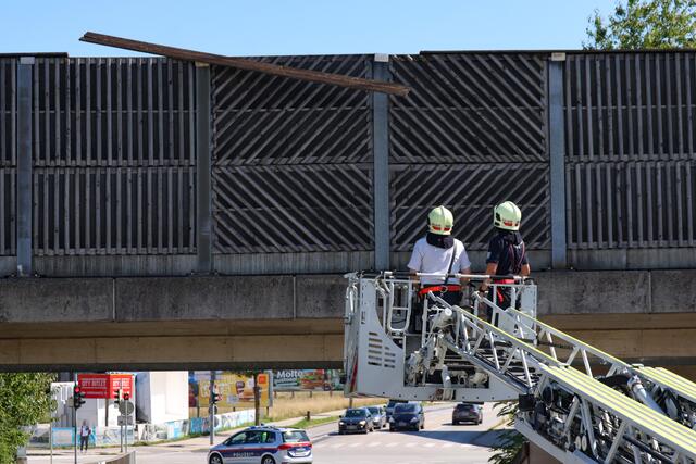 Starke Verwitterung an Lärmschutzwand einer Eisenbahnbrücke in Wels-Vogelweide: Die Feuerwehr konnte die lose gewordene Latte sicher entfernen.
