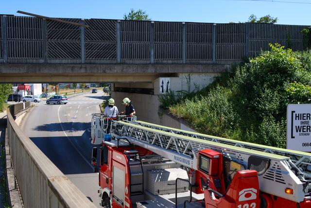 Starke Verwitterung an Lärmschutzwand einer Eisenbahnbrücke in Wels-Vogelweide: Die Feuerwehr konnte die lose gewordene Latte sicher entfernen.