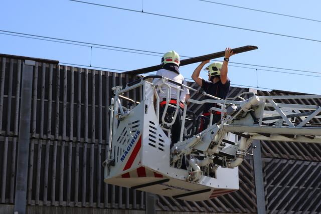 Starke Verwitterung an Lärmschutzwand einer Eisenbahnbrücke in Wels-Vogelweide: Die Feuerwehr konnte die lose gewordene Latte sicher entfernen.