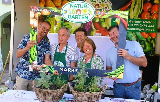 Die Markttour von "Natur im Garten" bietet den richtigen Rahmen für Infos zum naturnahe Garterln. Im Bild: Karl Ploberger (links) mit Bürgermeister Harald Leopold (Mitte) und Landtagsabgeordneten Josef Edlinger (rechts) sowie mit Gartengästen (mit Schürzen). 