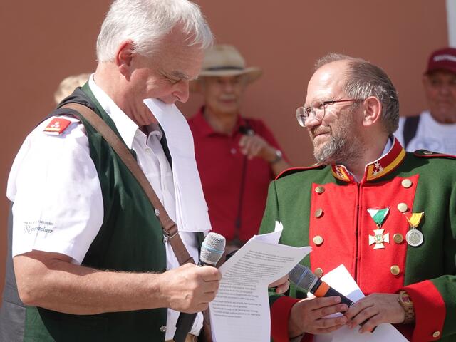 Nein, Mag. Alfred Baltzer isst kein Papier, muss aber ganz schnell seine Notizen in Einklang mit den ankommenden Riesen, Samsongruppen und Musikkapellen bringen. Rechts Bürgergarde Murau-Obmann Martin Lienhart.