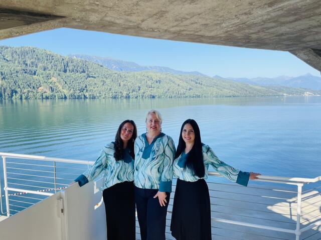 Das Türkis der Blusen spiegelt sich perfekt im Millstätter See wider: Mitarbeiterinnen des TVB Millstatt mit Büroleiterin in der malerischen Kulisse. V.l.n.r: Tanja Jamnig, Deborah Schumann, Jacqueline Springer. | Foto: Caro Berger