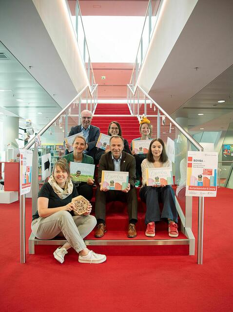 Nahmen nach der Buchpräsentation auf der roten Treppe Platz: Bibliothekarin Maud Koch (1. Reihe). Christine Tyma/Wissensstadt, Bürgermeister Bernhard Auinger, Ingrid Aspöck (2. Reihe). Stadt:Bibliotheks-Leiter Helmut Windinger, Eva Kraxberger/Wissensstadt und Felicitas Biller/edition mosaik (3. Reihe). | Foto: Stadt Salzburg/Rocio Escabosa