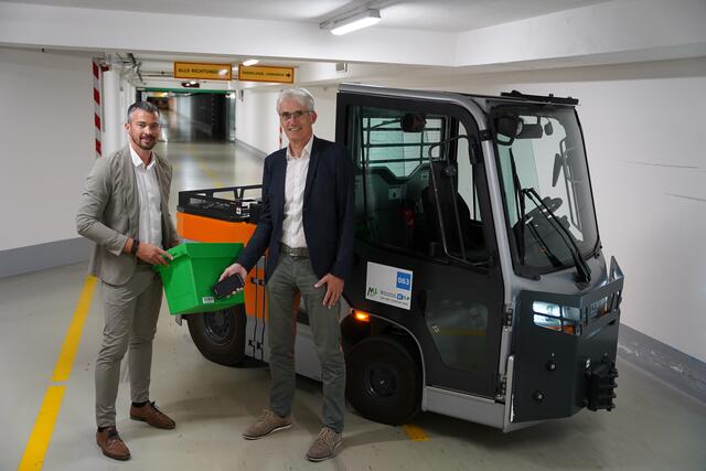 Michael Kazianschütz (Leiter für Wirtschaft und Logistik am Klinikum) und Markus Pedevilla (Leiter der Fachabteilung für Medizininformatik) vor einem der Elektroschlepper im Logistiktunnel des LKH-Universitätsklinikum Graz, in dem täglich mehrere tausend Güter – von Speisen über Apothekenwaren bis zur Wäsche, transportiert werden.  | Foto: KAGes