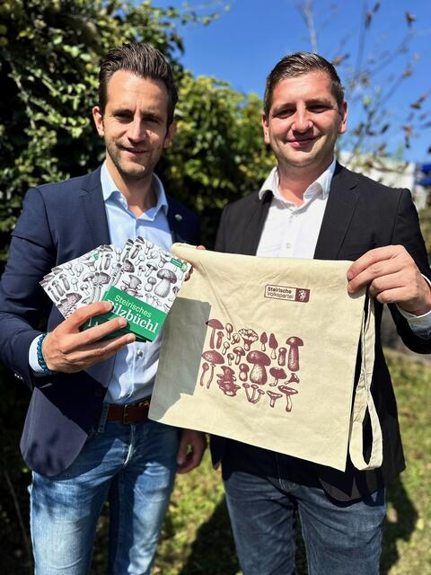 LAbg. Lukas Schnitzer und Bgm. Stefan Hold mit dem Steirischen Pilzbüchl und der praktischen Sammeltasche. | Foto: zVg