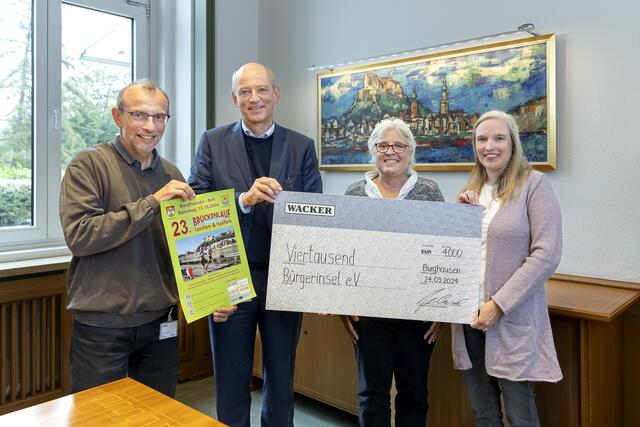 Mit einem Plakat vom Brückenlauf und dem symbolischen Spendenscheck (v. l. n. r.): Michael Schneiderhan, Wacker-Werkleiter Peter von Zumbusch, Heike Maser und Elli Huster. | Foto: Wacker Chemie AG