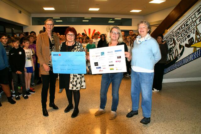 Ein Scheck über 1.500 Euro kommt dem Sozialfonds der Neuen Mittelschule zugute. Im Bild: Schulleiterin Sigrid Müller, Johanna Freudelsperger-Sagl, Evelyn Robertson und Waltraud Berchtold. Im Hintergrund die Schüler und Schülerinnen der Neuen Mittelschule Jennersdorf.  | Foto: Anna Maria Kaufmann