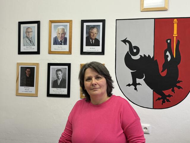 Bgm.in Christine Maria Tschol vor dem Wappen der Gemeinde und den Bildern ihrer Amtsvorgänger. | Foto: Reichel