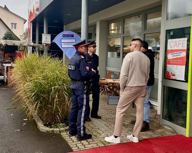 Der Sicherheitsbeauftragte der Polizeiinspektion St. Peter Rossmann und Michael Werginz beim Gespräch mit zwei Interessenten im Bereich der Apotheke | Foto: Polizei