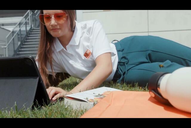 Auf der HLW-Schulwiese lässt sich die Pause auch zum Lesen nutzen. Greta Moser hat neben der HLW-Merchandise-Flasche auch „Das Flüstern der Biene“ dabei | Foto: Imagefilm der HLW Braunau 2024/25, Konzeption: HLW Braunau, Fa. Daniel Gepp