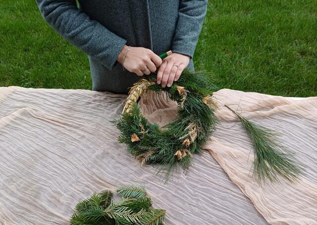 Als Erstes wird der Bindedraht am Strohrömer befestigt, dann das Grünmaterial Büscherl für Büscherl im Uhrzeigersinn angelegt und mit dem Draht befestigt. | Foto: Wilflingseder