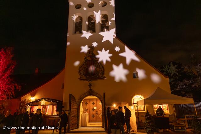 Sternenbeleuchteter Kirchturm und festliche Beleuchtung am Adventmarkt. | Foto: www.cine-motion.at / Ivanek