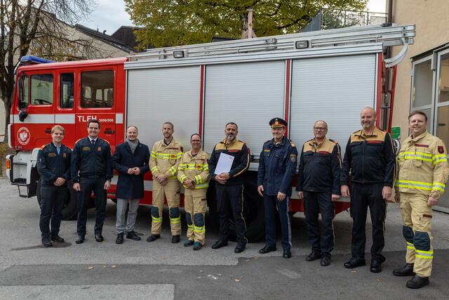 Feuerwehrmänner der Betriebsfeuerwehr der Justizanstalt, Christian Sermonet (2. v. r.) und Bernhard Grausam (5. v. r.), sowie Reinhard Potocnik, Leiter der Justizanstalt (4. v. r.), nehmen das Tanklöschfahrzeug der Freiwilligen Feuerwehr Hötting entgegen.  | Foto: M. Freinhofer
