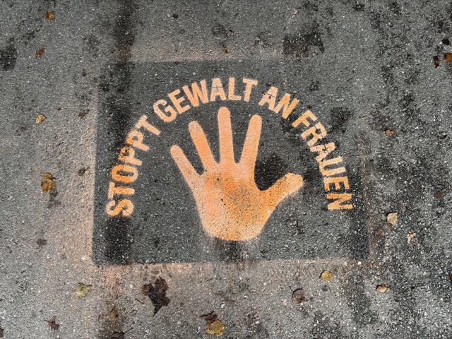 Die Schüler sprühen mithilfe einer Schablone Bilder, um auf Gewalt gegen Frauen aufmerksam zu machen.