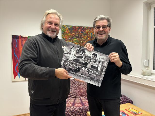 Ein Jahreskalender mit Wiener-Neustadt-Motiven von Fotokünstler Franz Baldauf (rechts). MeinBezirk-Redakteur Peter Zezula freut sich über diese vorweihnachtliche Überraschung. | Foto: MeinBezirk
