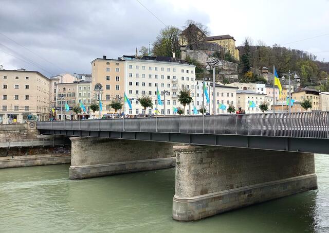 Von 2. bis 9. Mai 2025 werden Flaggen entlang der Staatsbrücke in der Stadt Salzburg an das Kriegsende vor 80 Jahren (1945) und die Gründung der Zweiten Republik erinnern. Für die Gestaltung der Motive sind heimische KünstlerInnen gefragt. | Foto: H.Bachinger 