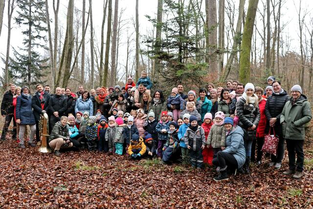Kinder, Erwachsene und Personal mit dem Waldchristbaum im Hintergrund