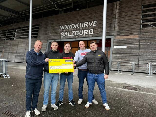 Von links: Dominik Steinbichler von der Salzburger Kinderkrebshilfe und die treuen Fans des FC Red Bull Salzburg bei der Scheckübergabe. | Foto: Nordkurve Salzburg