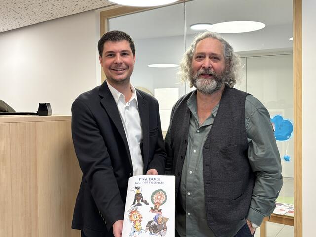 Bürgermeister Patrick Holzknecht und Künstler Peter Riml präsentieren das neue Malbuch der Wenner Fasnacht. | Foto: Dorn