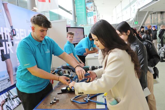 Den Beruf der Installateure stellten Berufsschüler vor. Kilian zeigt Aynisa, wie sie mit seinem Werkzeug ein Rohr-Herz biegen kann. | Foto: Edith Ertl