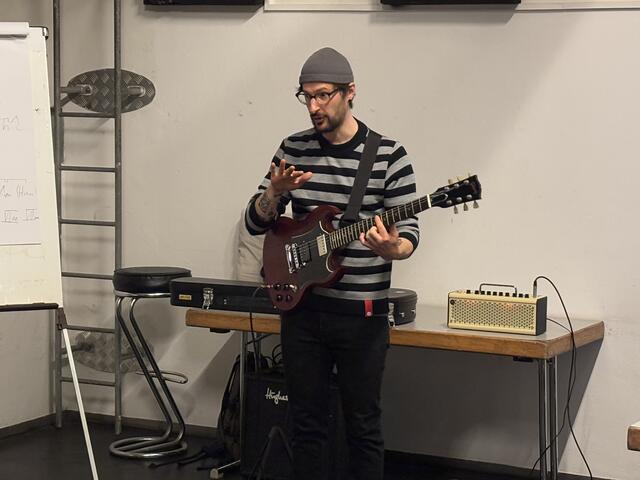 Simon Paulus leitete den Workshop. Der Singer und Songwriter aus der Stadt Salzburg griff des Öfteren auch selbst zur Gitarre, um das komplexe Thema verständlicher zu machen. | Foto: Schrofner