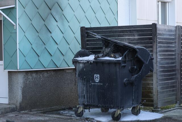 Brennender Altpapiercontainer in Wels-Lichtenegg: Durch das Einschreiten der Feuerwehr konnte ein Übergreifen der Flammen auf die Fassade verhindern.