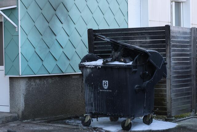 Brennender Altpapiercontainer in Wels-Lichtenegg: Durch das Einschreiten der Feuerwehr konnte ein Übergreifen der Flammen auf die Fassade verhindern.