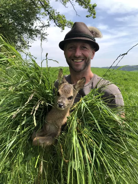 Roland Seiringer aus Rutzenham bei der morgendlichen Kitzrettung. Das Jungtier darf nur mit Handschuhen und Gras berührt werden. | Foto: A. Helmberger