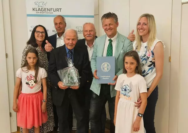 Scheider überreichte Direktor Oberschulrat Horst Jellitsch den Gläsernen Lindwurm der Landeshauptstadt. Bruder, Sohn, Schwiegertochter, Enkelin und die beiden Urenkelinnen waren bei der Ehrung mit dabei. | Foto: StadtKommunikation/Tilli