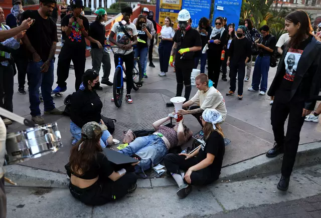 Eine Demonstrantin, die von einem Auto angefahren wurde, wird unterstützt, während sie während eines Protestes am 15. Juni auf dem Boden liegend durch ein Megafon spricht.  | Foto: David Swanson / REUTERS / picturedesk.com